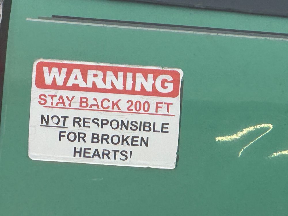 Warning sticker on a truck reading: “WARNING / Stay back 200 ft / Not responsible for broken hearts”