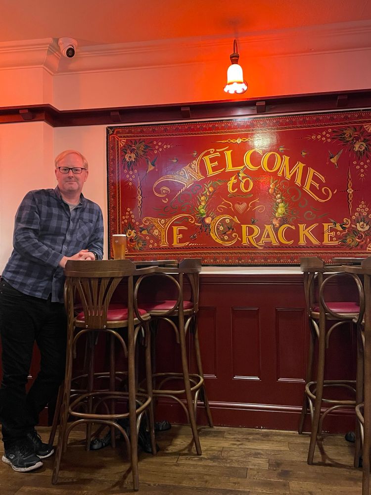 Paul from Big Sort stood by the Welcome to Ye Cracke sign inside the pub. He has a pint of Ossett Silver King.