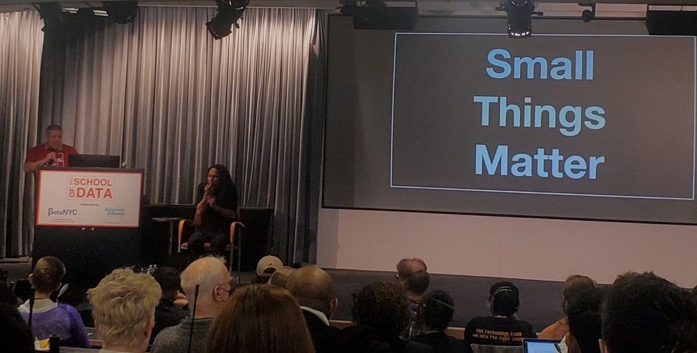 Speaker at podium giving presentation in front of slide that says "small things matter"