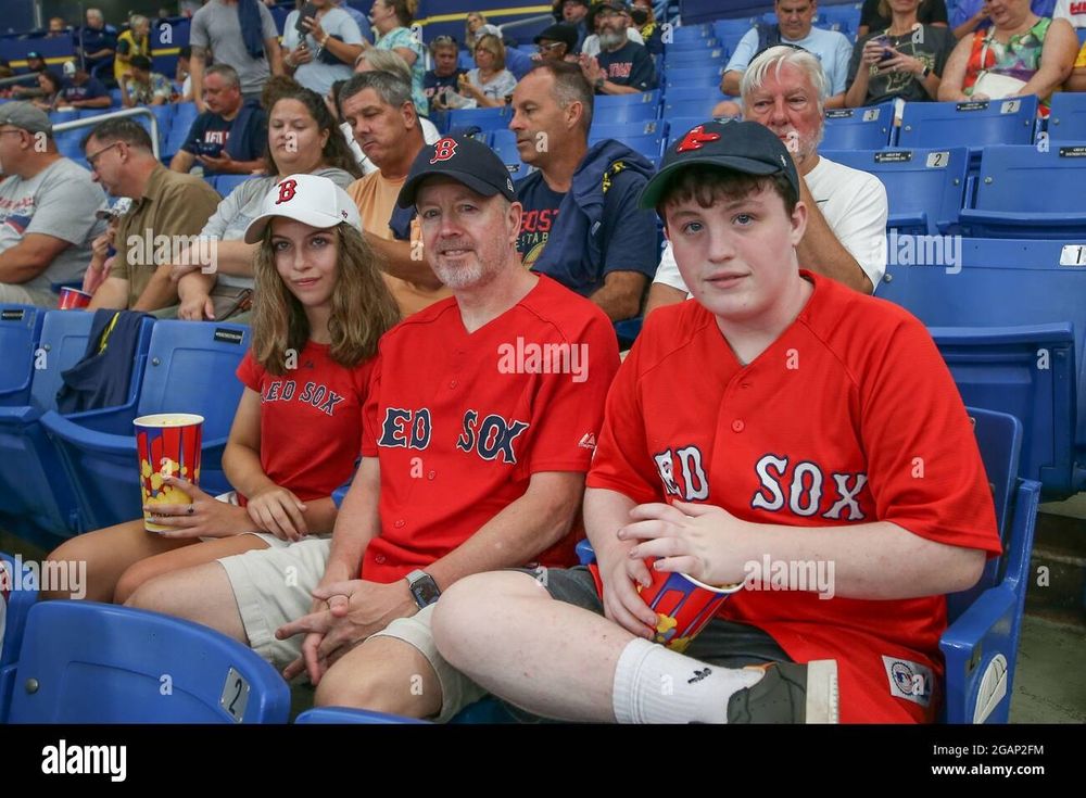 Boston red sox fans in red jerseys, caps, and shorts. 