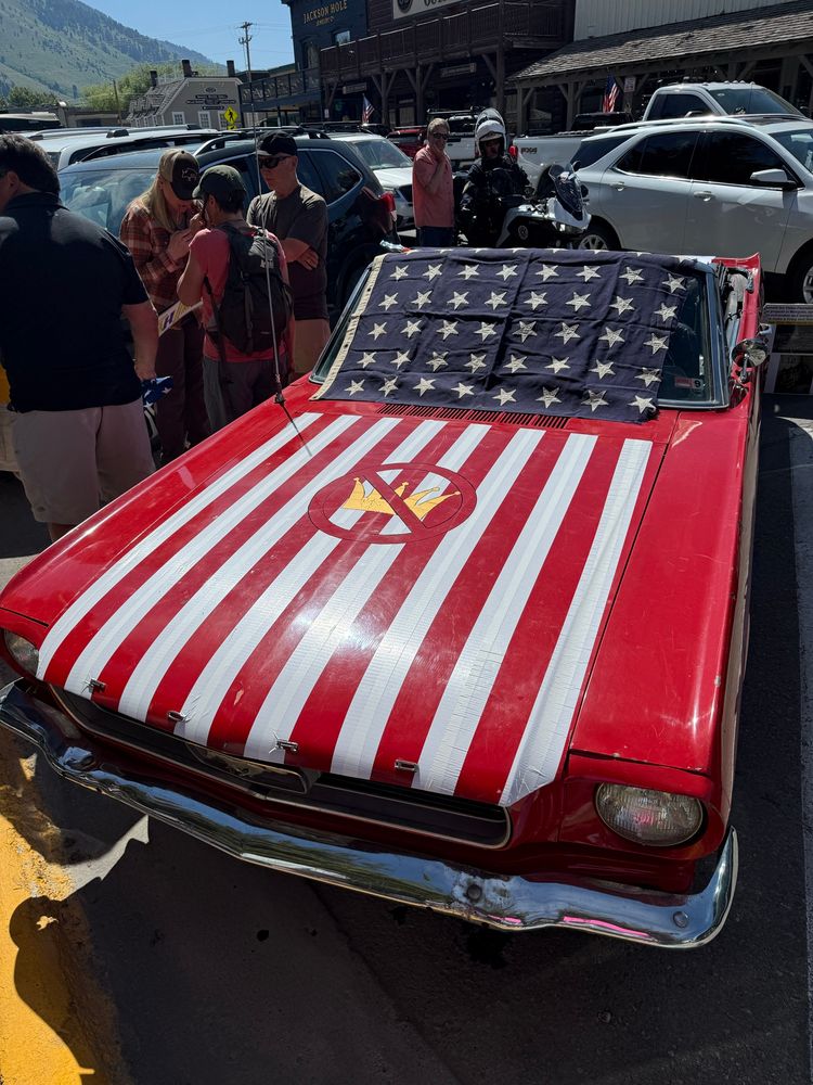 A red ford mustang has been decorated to look like an American flag 