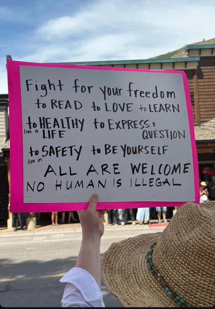 A sign reads: fight for your freedom to read, to love, to learn, to live a healthy life, to express and question, to live in safety and be yourself. All are welcome. No human is illegal.
