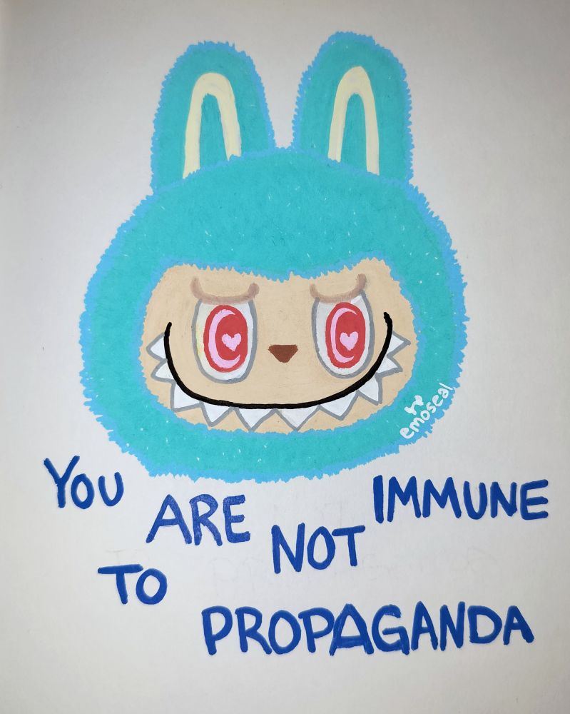 A paint pen drawing of a blue Labubu head with the text "YOU ARE NOT IMMUNE TO PROPAGANDA" in the style of the Garfield meme