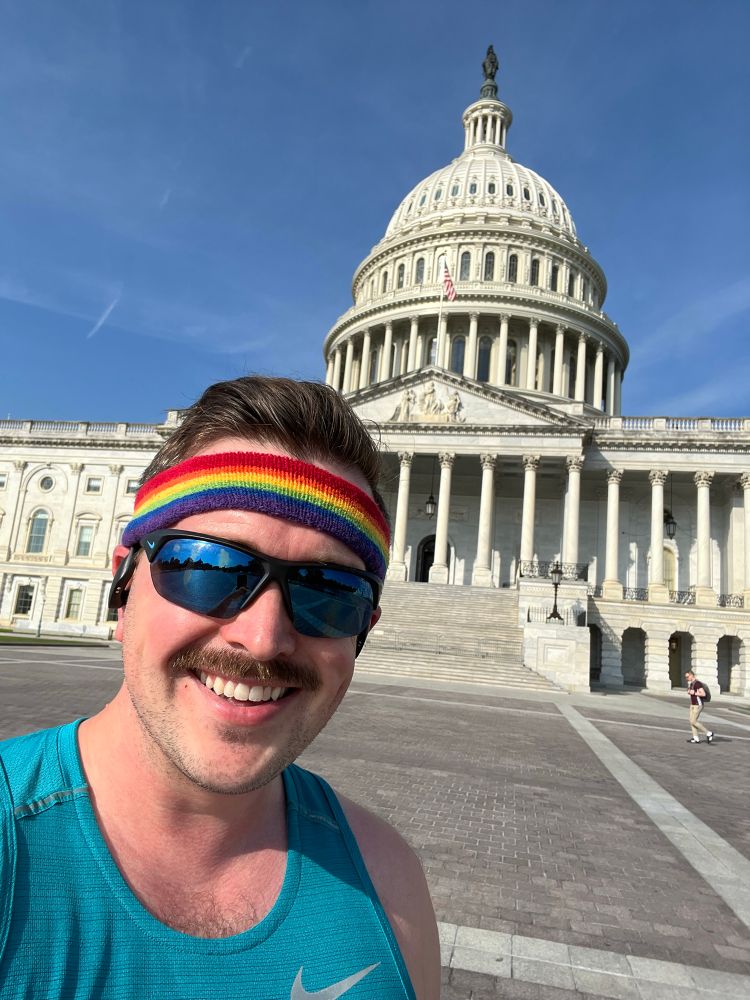 Me in a running tank top and a rainbow headband standing in front of the US Capitol dome