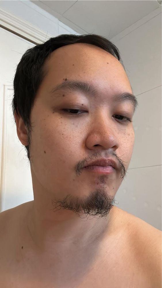An Asian topless AMAB person with a goatee of sorts wondering what can be done with it 