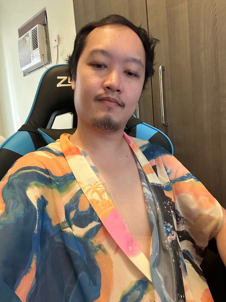 A topless Asian man in a patterned sleeveless cardigan like thing I don’t know women’s fashion enough to know what I bought 