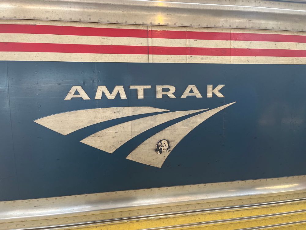 A sticker with Dolly parton’s face on the insignia of an Amtrak train 