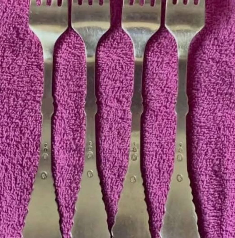 a visual illusion: what appears to be some strangely shaped pink pieces of cloth are actually the background on which several forks are laying 