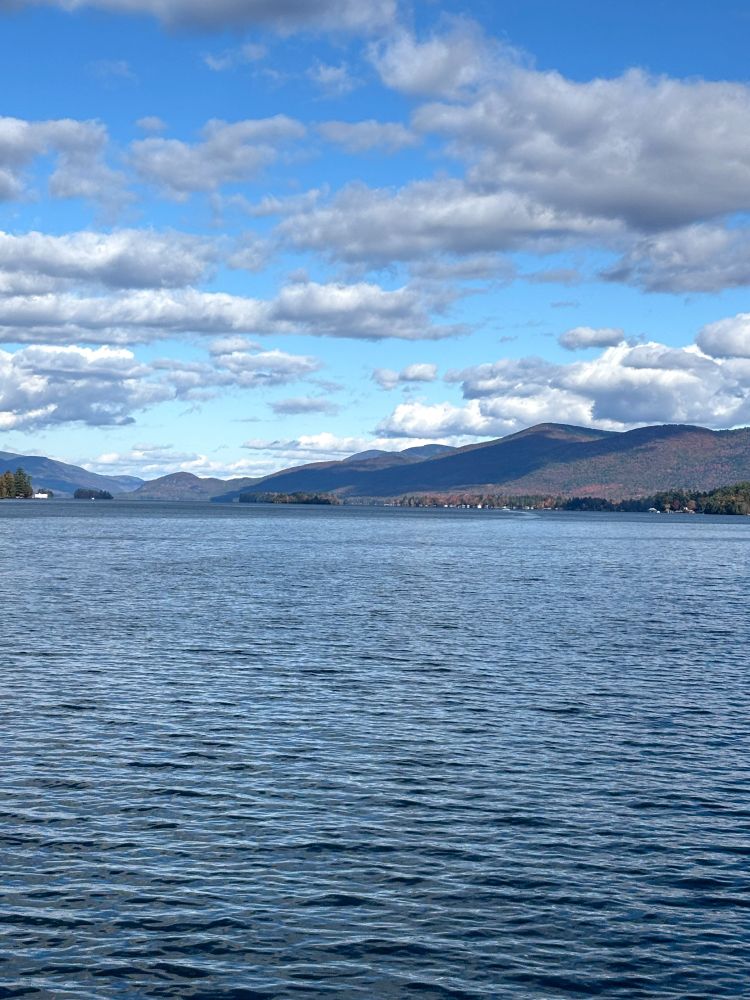 A view of the lake and the mountains behind as clouds make shadows across the landscape.