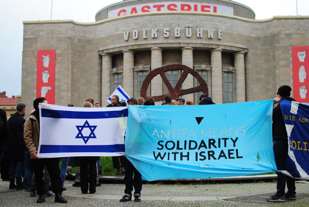 Menschen mit Israelfahne und Transparent mit Aufschrift "Antifa means solidarity with Israel" vor dem Gebäude der Volksbühne