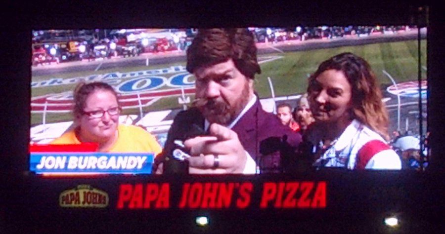 This is a picture of me on the big screen at Charlotte motor Speedway playing a game with two contestants. I am dressed up and doing a goof of Ron Burgundy from the anchorman movies.