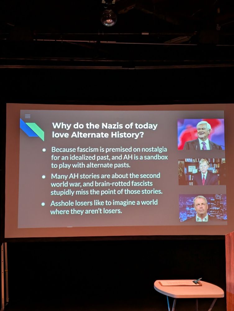 Photo of a slide on stage.
"Why do the Nazis of today love Alternate History?
- Because fascism is premised on nostalgia for an idealized past, and AH is a sandbox to play with alternate pasts.
- Many AH stories are about the second world war, and brain-rotted fascists stupidly miss the point of those stories.
- Asshole losers like to imagine a world where they aren't losers.