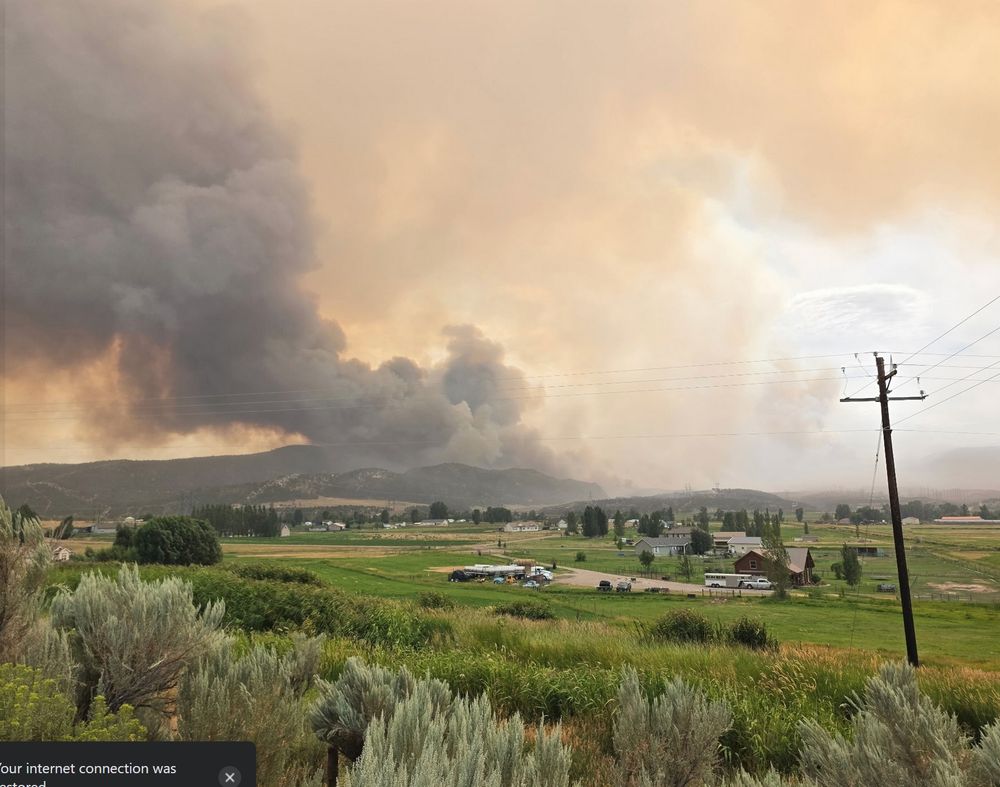 rural community with a large fire on the hilltop beyond