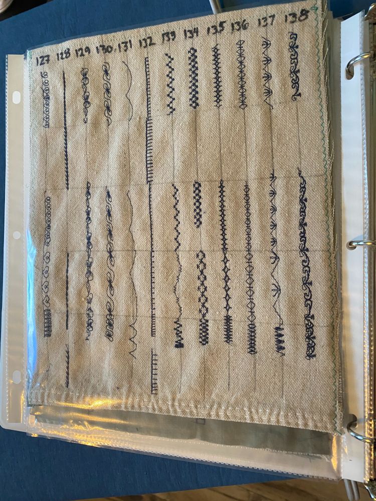 muslin fabric with lines of stitching down in columns with numbers at the top indicating which machine stitch it is.  stitches change in length and width from top to bottom.