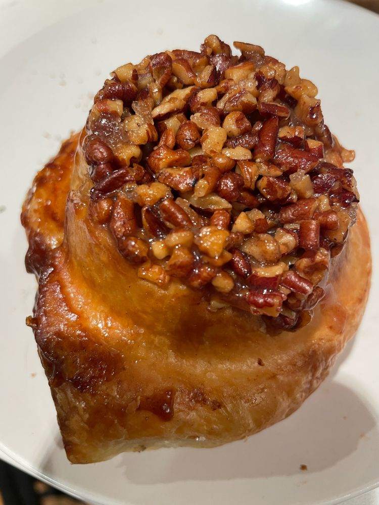 A sticky bun (a coiled up pastry) topped with loads of walnuts