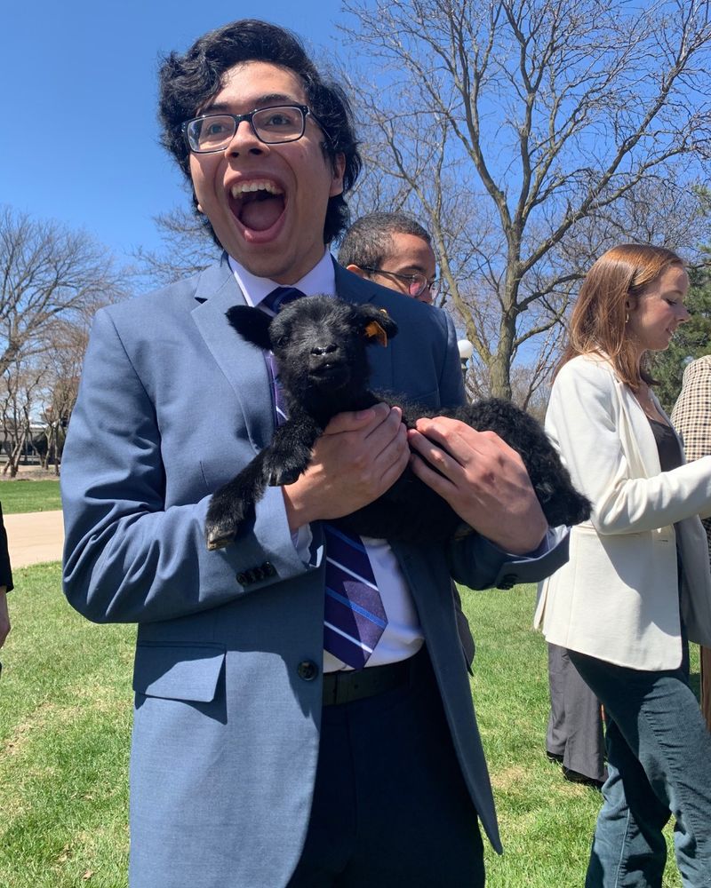 Emilio holding a lamb with his mouth agape
