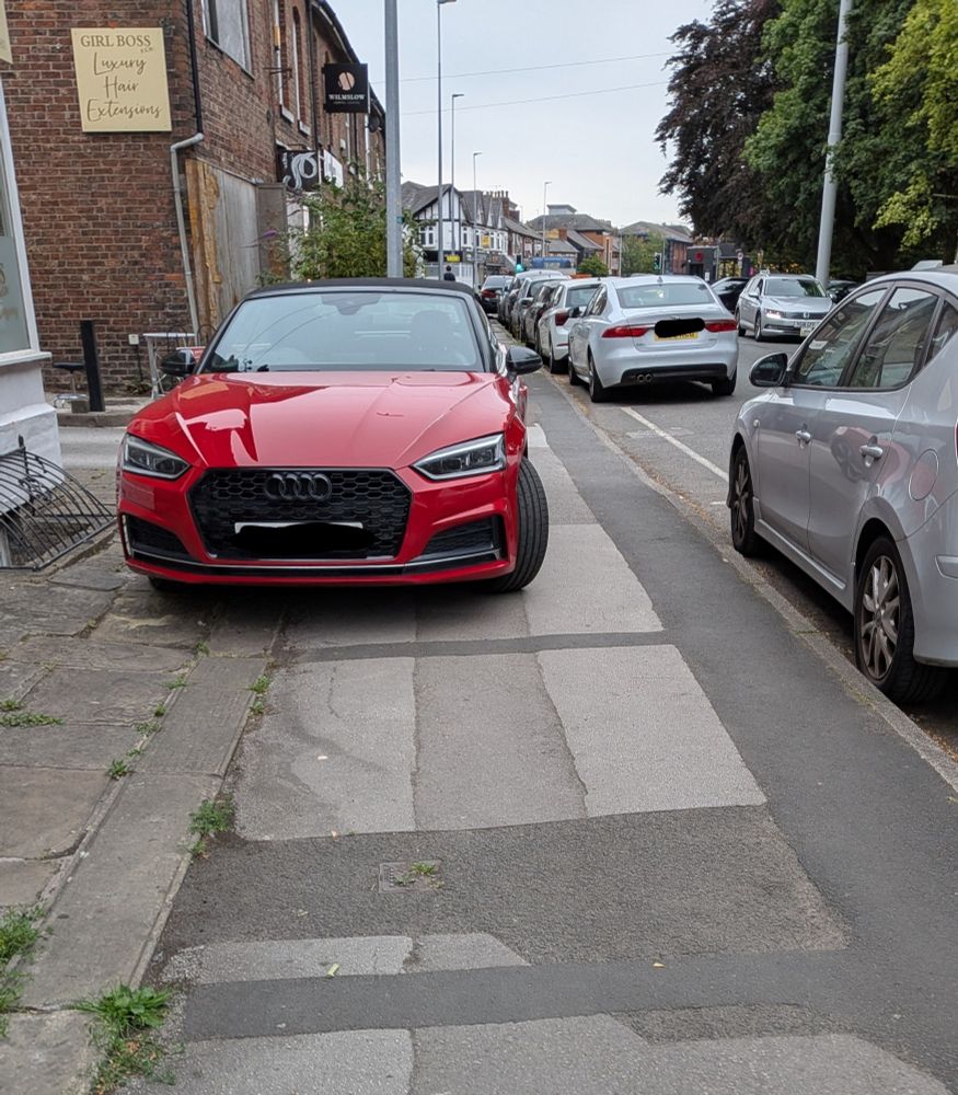 Red Audi car parked completely on the pavement.