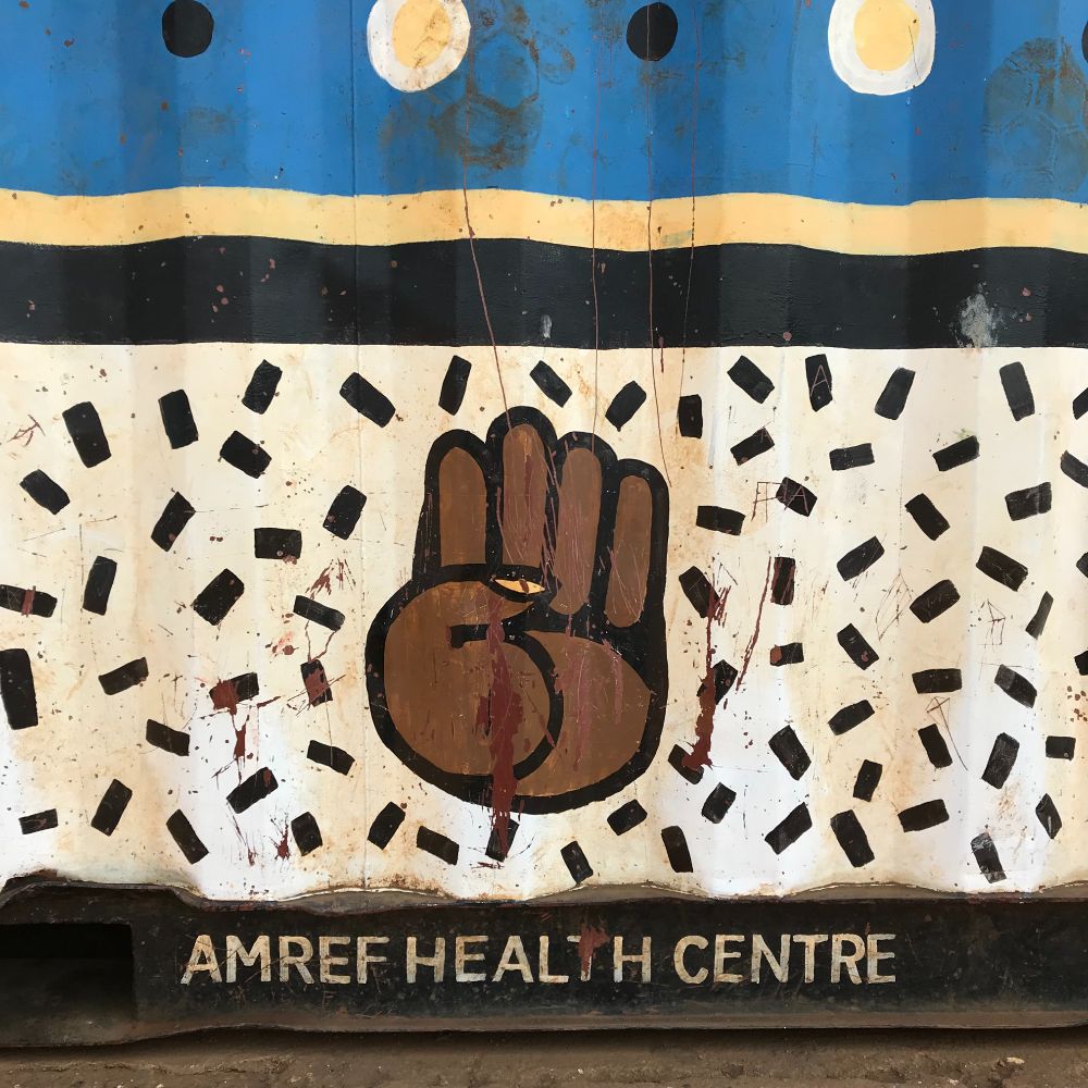 Painting of a brown fist on a wall over a saying AMREF Health Centre