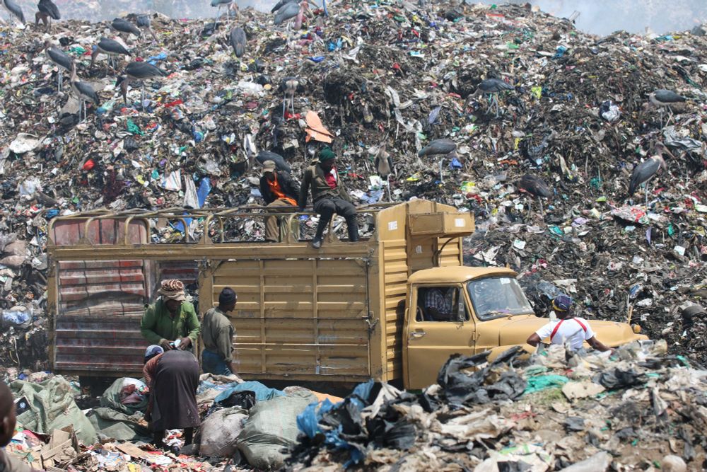 People collecting things from a mountain of waste