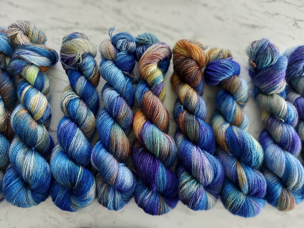 Blue, orange, indigo, soft yellow skeins with faint green in a row. 