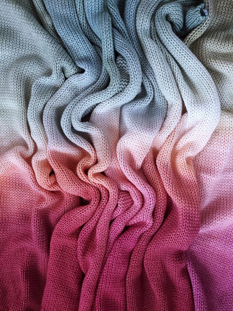 Bunched up yarn blanks in a gradient from sage green to orange to plum