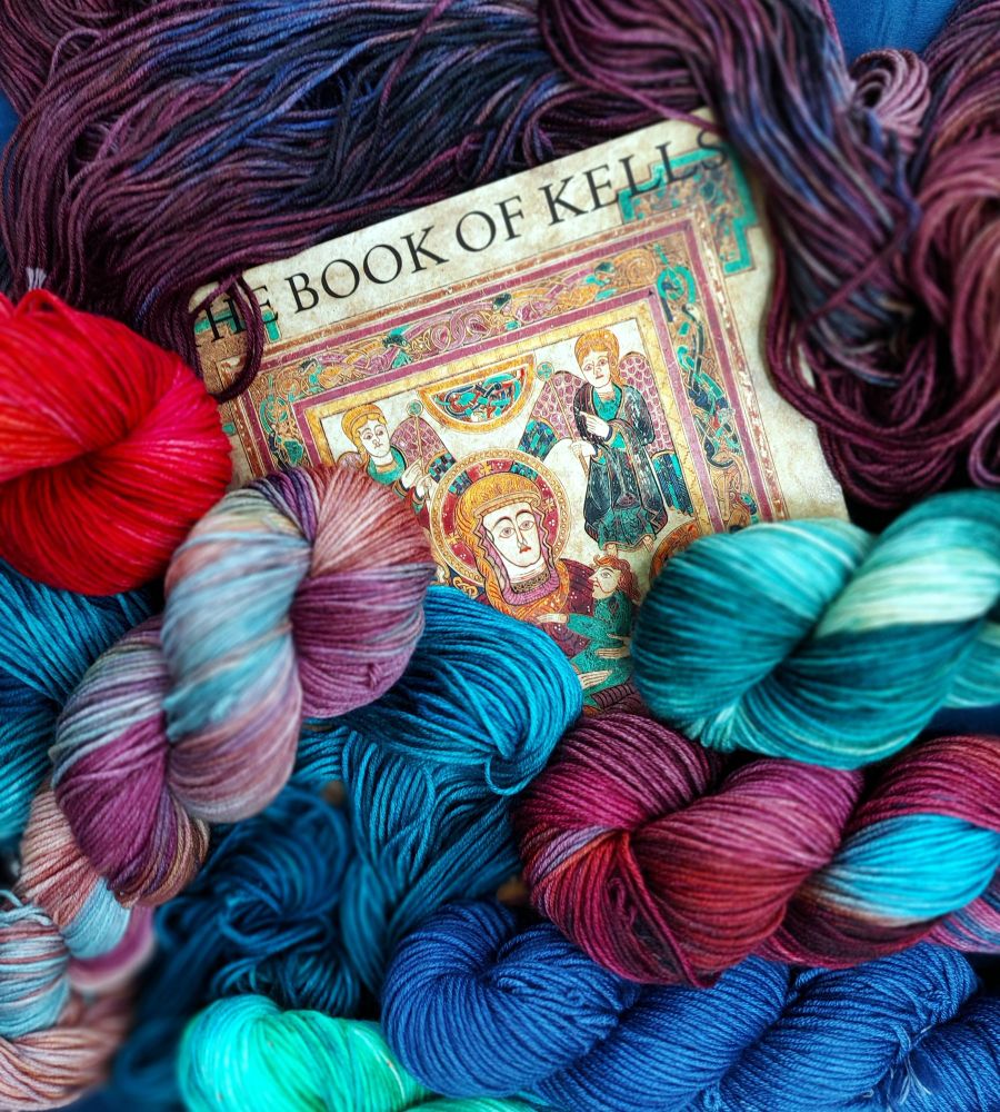 Book of Kells image surrounded by various colorful skeins of yarn 