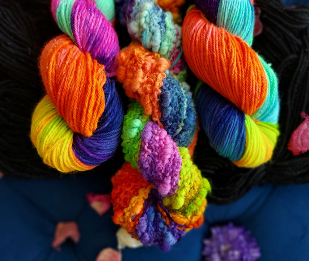 Rainbow yarn skeins coiled on a line. The middle of 3 skeins is a bubble chunky base 