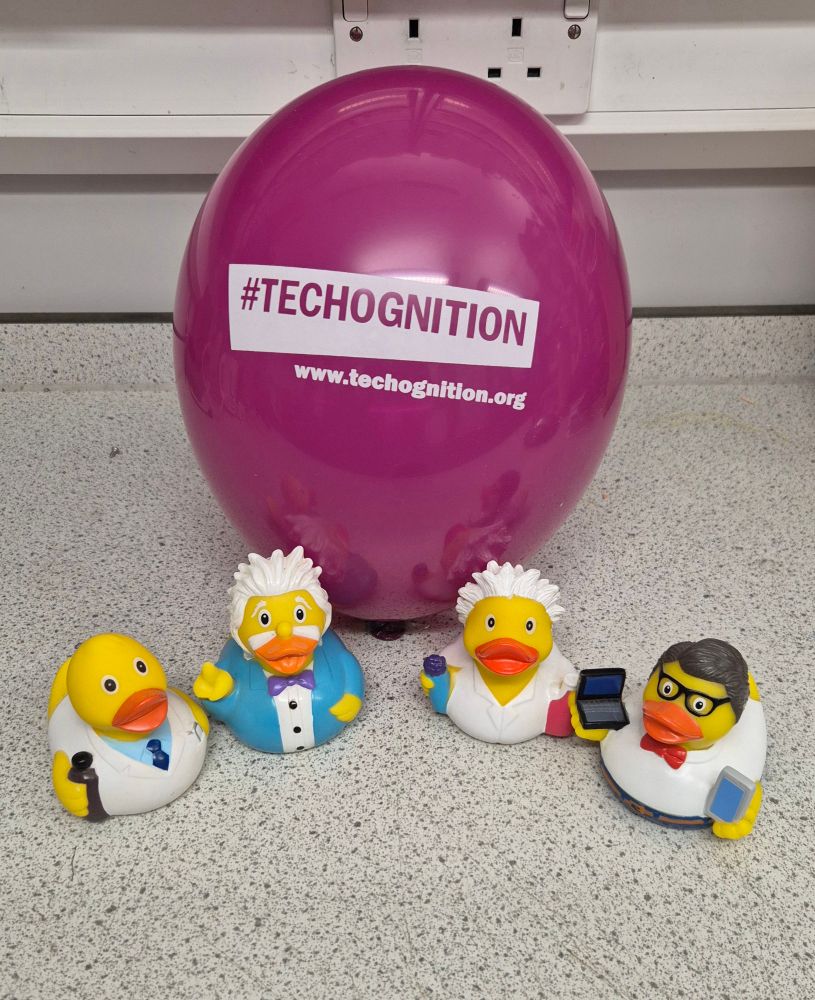 A purple #TECHOGNITION balloon surrounded by 4 rubber ducks. They are a pharmacist, Albert Einstein, a chemist, and an IT duck.