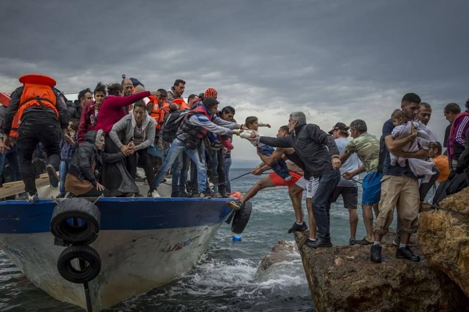 Des migrants arrivent sur l'île grecque de Lesbos à bord d'un bateau de pêche, le 11 octobre 2015. (ANTONIO MASIELLO / NURPHOTO / AFP)