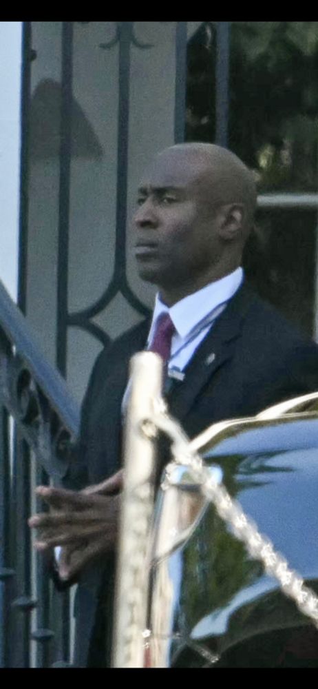 A close-up of one of trump's secret service agents. He's bald and stern faced, like someone doing their best impression of Lex Luthor. And I know what you are thinking, yeah, man, a lot of people are bald and stern faced. It doesn't make them super villians. But get this! This man is actually, no joke, walking around with his fingers steepled. For real! STEEPLED FINGERS! The only thing missing is a spandex suit with a big skull sewn on the front. 