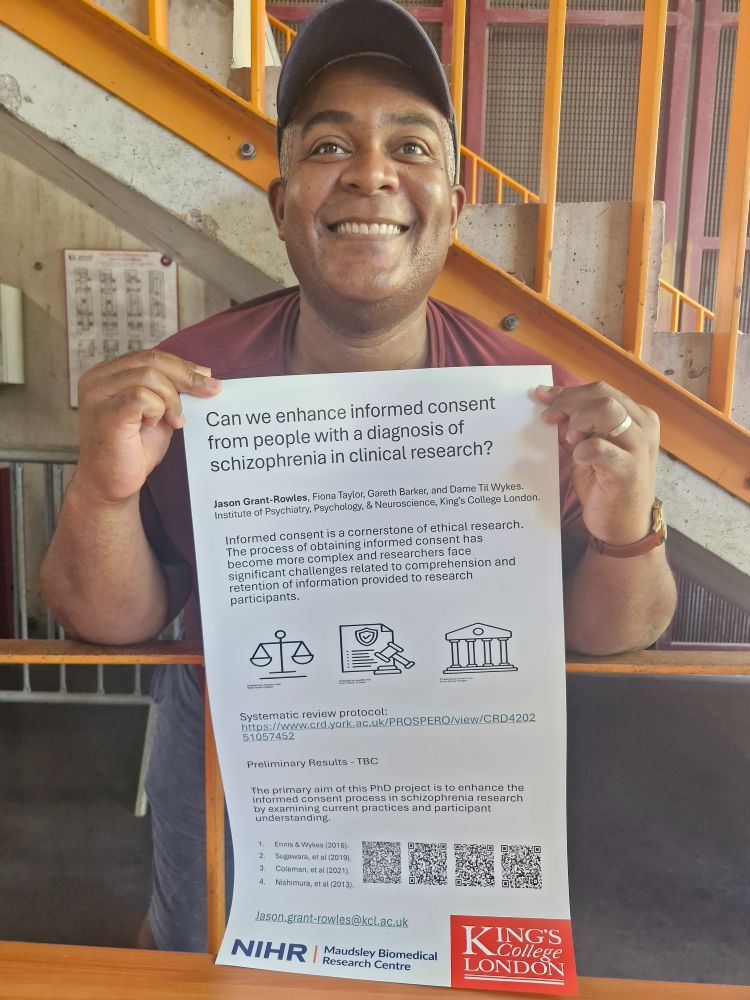Man smiling at camera holding A3 poster
