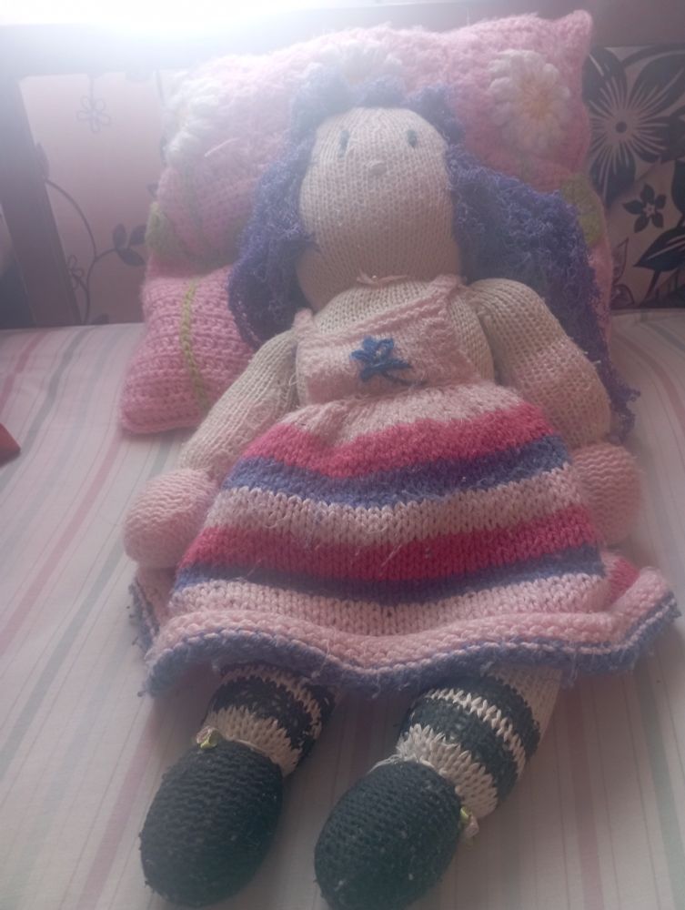Doll resting on pillow, both made with crochet technique