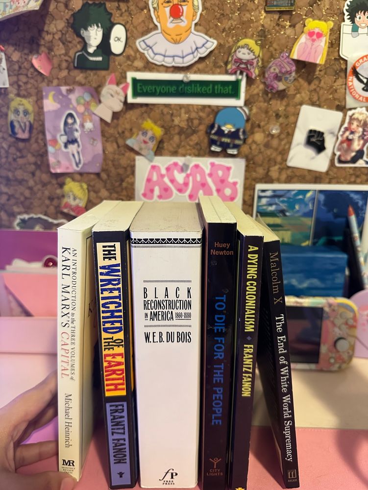 A photo of the books Wretched Of The Earth by Frantz Fanon, Black Reconstruction in America by W.E.B. Du Bois, To Die For The People by Huey Newton, A Dying Colonialism by Frantz Fanon”, “The End Of White World Supremacy by Malcom X”