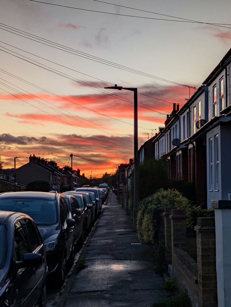 A Hertfordshire street at sunset with terraced houses and cars