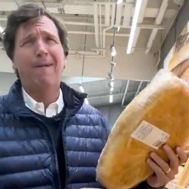 Tucker Carlson making a truly upsetting face after enjoying the smell of bread in a Russian grocery store. He is wearing his Swanson Soup Heir uniform of dress shirt under a preppy lil sweater. He also has a puffer jacket over the top. It's giving après-ski après-relévance. This is a screengrab from a deranged propaganda vid he made where he was like, wait. Russians eat... food? Just like meeeee?