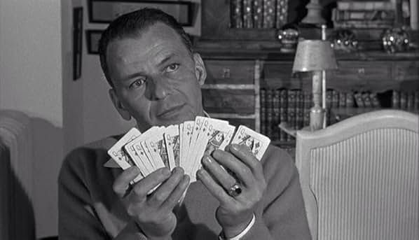 Frank Sinatra, holding a fanned deck of cards in both hands.