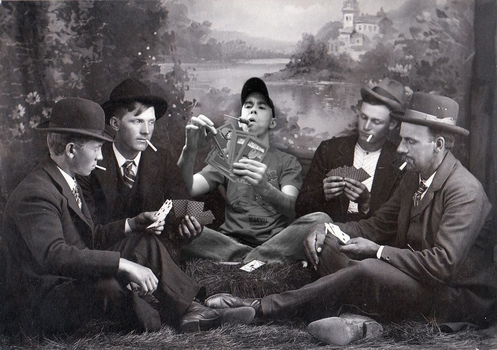 Four Depression era guys in suits and hats sit on the ground, smoking cigarettes and playing poker. In the middle of this group, sits an odd-looking anachronistic doofus (me). He’s wearing a baseball cap and a Spider-Man t-shirt, has one of those long, twisty lollipops in his mouth, and has labeled “Go Fish” cards in his hand.