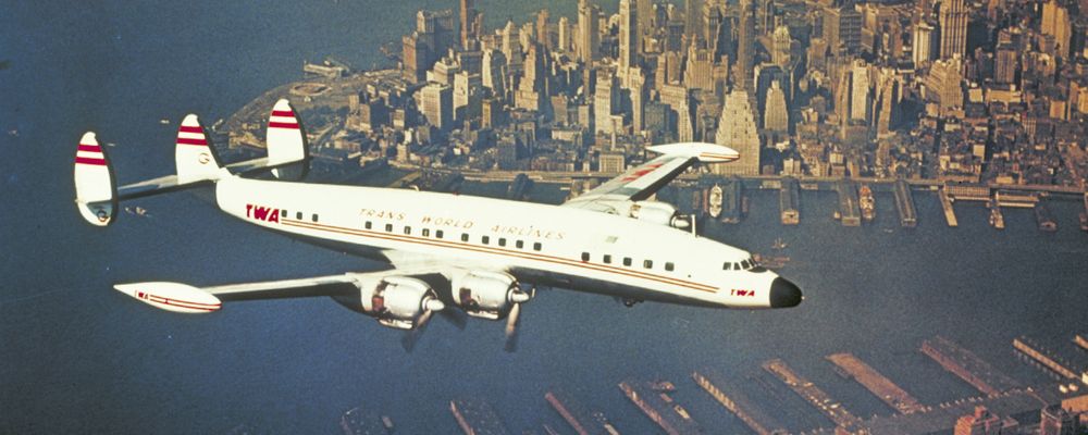 Image of a Lockheed Constellation flying over New York's downtown.
