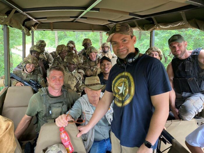 Director Patrick Garcia standing in an open aired suv in front of the cast and crew of Lost Horizon.