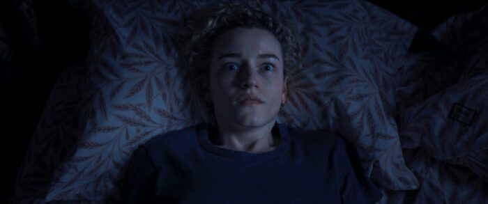 A terrified woman lays in bed in the dark in Weapons.