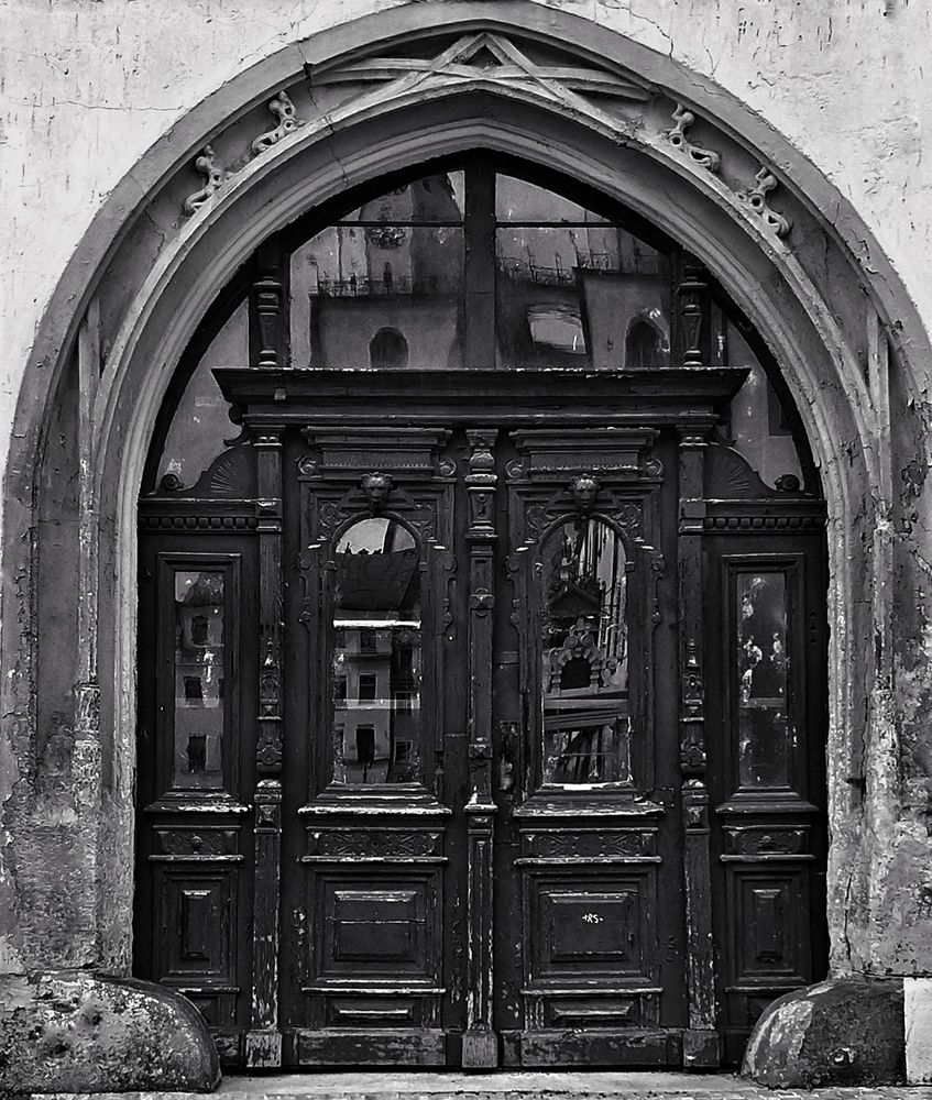 Alte Holztür mit steinernen Bogen. Schwarz-weiß Aufnahme aus der Lutherstadt Wittenberg. 
