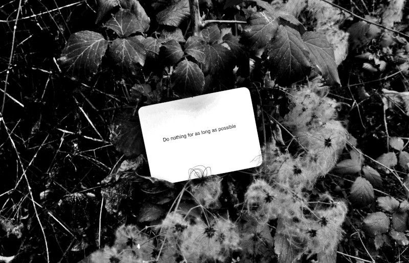 A black-and-white photo of an Oblique Strategy card. The card reads: 'Do nothing for as long as possible'.