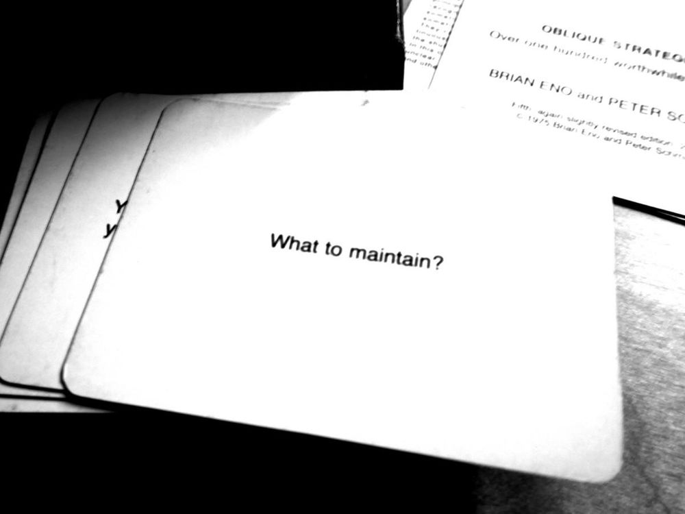 A black-and-white photo of an Oblique Strategy card. The card reads: 'What to maintain?'.