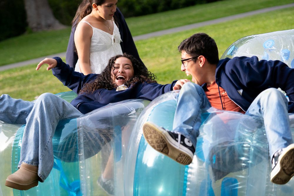 Two attendees laugh while laying atop inflatable bumper balls. (Photo by Adam Lau / Berkeley Engineering)