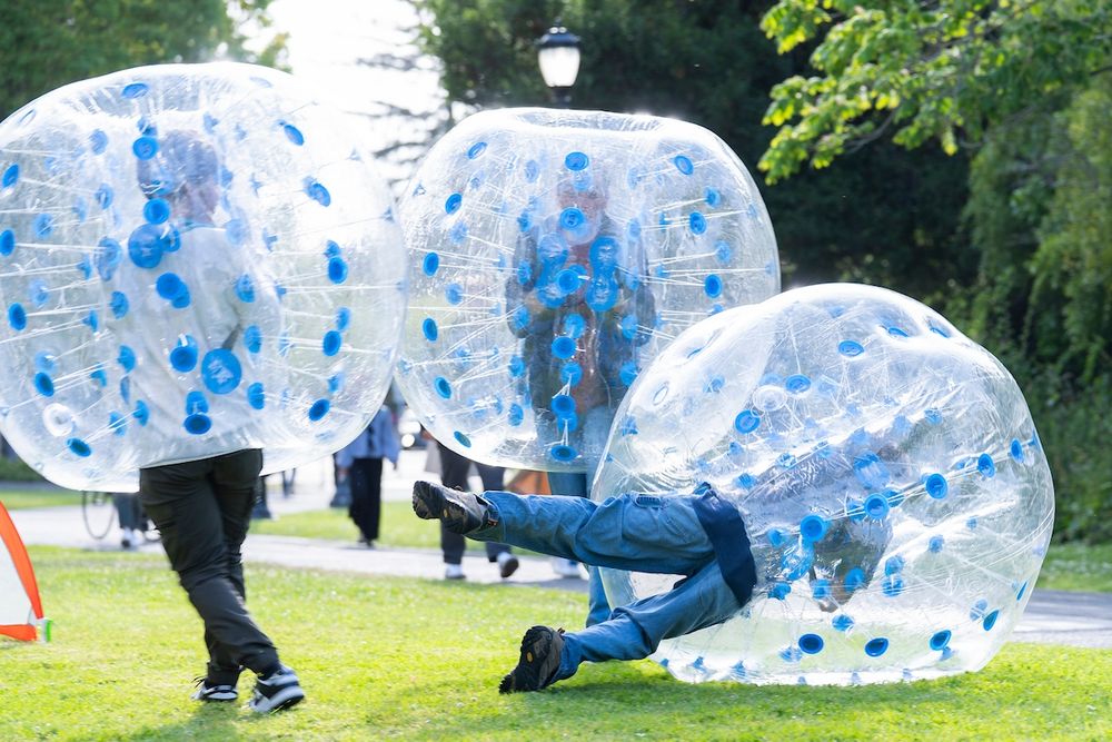 Three attendees wearing inflatable bumper balls, one falling over. (Photo by Adam Lau / Berkeley Engineering)