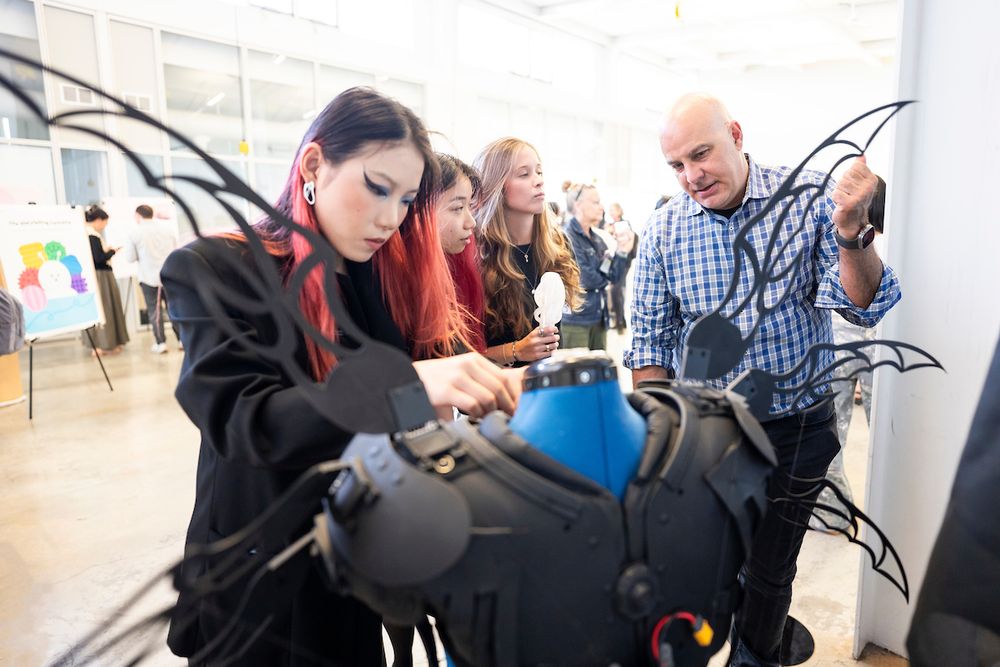 Four attendees gather around a project featuring a black vest with wings. (Photo by Adam Lau / Berkeley Engineering)