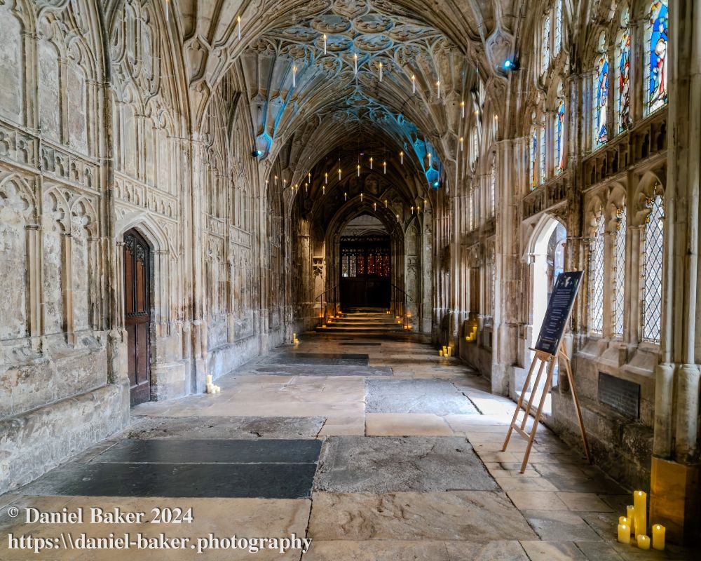 photo of the cloisters at Gloucester cathedral with Christmas decorations shaped like candles hanging from the ceiling 