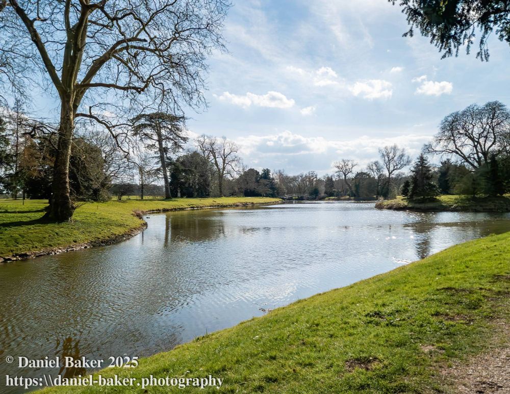 view of a lake glistening in the sun and surrounded by green grass and trees