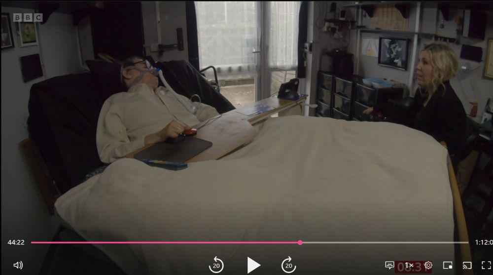 screenshot from iplayer of Daniel Baker laying in his bed talking to Nikki Fox