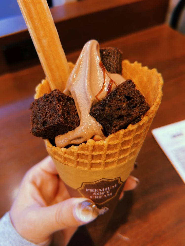 ミニストップの「プレミアムソフト -ごほうびショコラ-」を左手で持っている写真